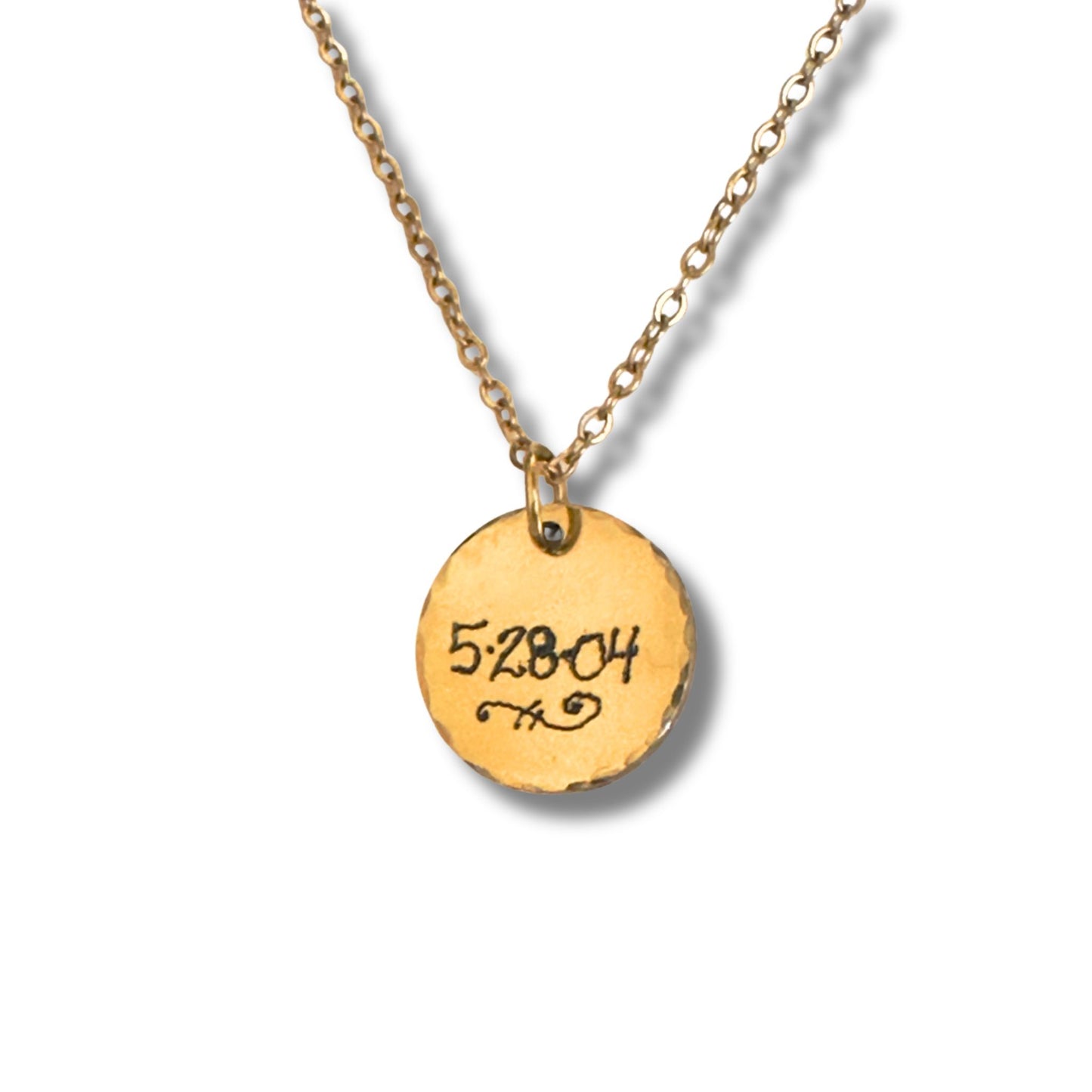 Engraved gold pendant in script featuring a date close up