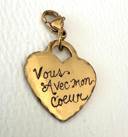 Gold heart-shaped charm with engraved text and clasp on a white background