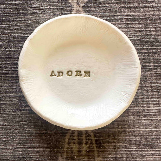 round white trinket dish with  the word adore in gold letters